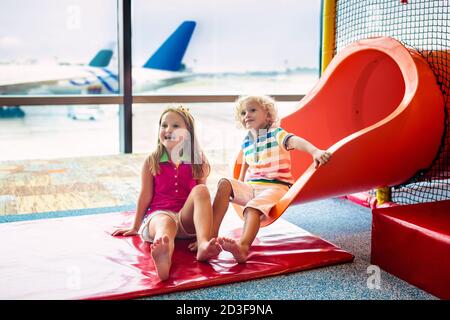 Kinder auf dem Spielplatz am Flughafen. Kinder schauen auf das Flugzeug. Reisen und Fliegen mit Kind. Familie am Abflugsteig. Urlaub und Reisen mit kleinen Kindern. Stockfoto