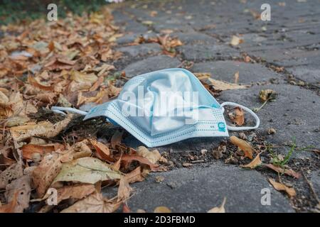 Weggeworfene Gesichtsmask auf dem Bürgersteig. Deutschland Stockfoto