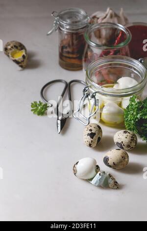 Zutaten für selbstgemachte mariniert marinierte Wachteleier. Eier in Kunststoffbox, Tomatensauce, chili peppers, Sardellen in Töpfen, frischen Grüns, Schere, ol Stockfoto