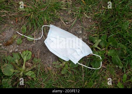 Weggeworfene Einweg-Gesichtsmask auf dem Boden. Ostfriesland. Deutschland. Stockfoto