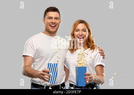 Glückliches Paar in weißen T-Shirts, das Popcorn isst Stockfoto