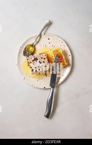 Bio Honig in den Waben mit Löffel und Messer in beschmutzt Keramikplatte auf weißem Hintergrund. Flach, kopieren Raum Stockfoto