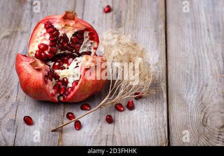 Geöffneter reifer Granat mit Samen auf rustikalem Holzhintergrund Stockfoto