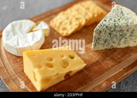 Verschiedene Käsesorten und Cracker auf Holzbrett Stockfoto