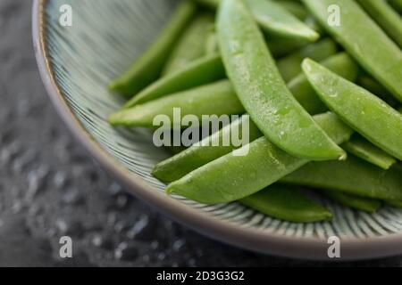 Erbsen in Schüssel auf nassem Schieferstein Hintergrund Stockfoto