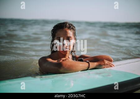 Porträt einer jungen europäischen Surferin mit ihren Händen Auf ihrem Surfbrett