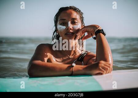 Porträt einer jungen europäischen Surferin mit ihren Händen Auf ihrem Surfbrett