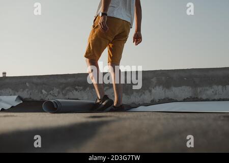 Arbeiter trägt PVC-Membranrolle auf Dach sehr vorsichtig Stockfoto