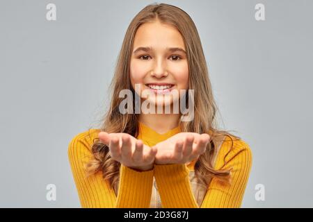 Teenager-Mädchen hält etwas auf leeren Händen Stockfoto
