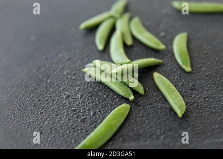 Erbsen auf nassem Schieferstein Hintergrund Stockfoto