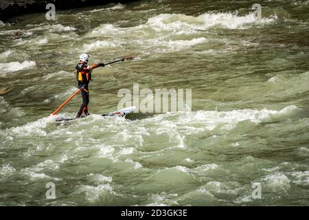 Mann auf seinem Stand Up Paddle Boarding (SUP), paddelt stromaufwärts in den Stromschnellen der Etsch in der Innenstadt von Verona. Venetien, Italien, Europa Stockfoto