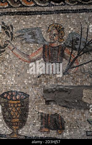 Christliche Version von Victoria, römische Göttin des Sieges. Details des riesigen 300s n. Chr. Mosaiks in der Basilica di Santa Maria Assunta in Aquileia, Friaul-Julisch Venetien, Italien. Geschaffen von frühen christlichen Künstlern, als sich das Christentum über das Römische Reich verbreitete. Hier hält die geflügelte römische Göttin einen Lorbeerkranz und einen Palmenzweig und steht neben einem großen christlichen Kelch, wie er in der Eucharistischen oder Heiligen Kommunion verwendet wurde. Stockfoto