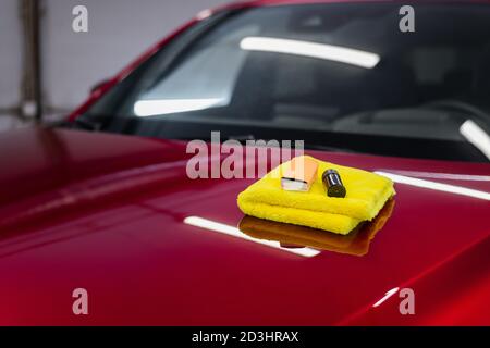 Nahaufnahme eines Beschichtungssets: mikrofaser, Schwamm-Applikator und Flüssigglas-Nano-Schutz auf eine Autohaube auftragen. Vorbereitung für die Anwendung Spezial Stockfoto