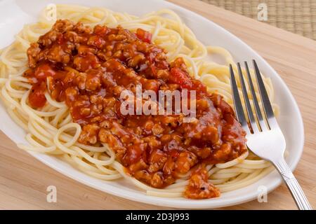 Teller mit leckeren Spaghetti und Pasta-Sauce auf einem hölzernen Hintergrund Stockfoto