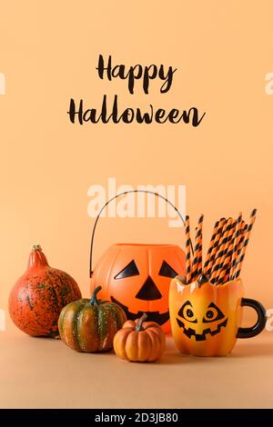 Halloween blank oder Einladung mit Party-Dekorationen, Bonbonschüssel, Kürbisse, Süßigkeiten, niedlichen Becher mit Trinkhalm auf orangefarbenem Hintergrund. Vertikale Kompos Stockfoto