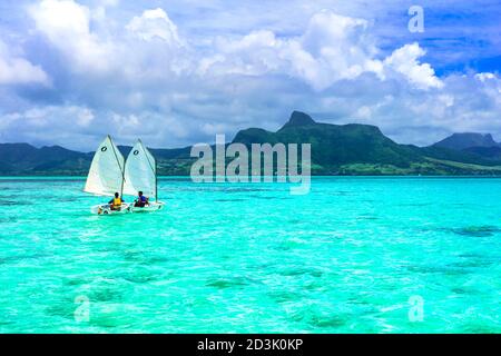 Atemberaubende Blue Bay mit transparentem türkisfarbenem Meer. Jungs in Segelbooten. Mauritius-Insel. Januar 2020 Stockfoto