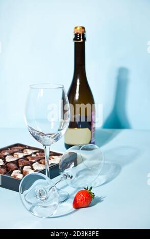 Leere Gläser für Champagner oder Wein. Schachtel Pralinen und Flasche auf dem Hintergrund Stockfoto