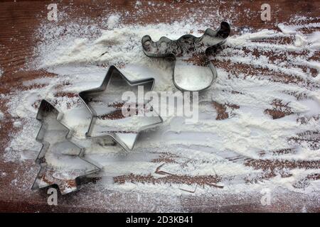 Rentier, weihnachtsbaum und Stern Lebkuchen Ausstechformen und Mehl wie ein Schnee auf Holz Hintergrund. Weihnachten Essen Hintergrund. Draufsicht Stockfoto