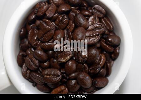 Kaffeebohnen auf Tasse Kaffee isoliert auf weißem Hintergrund.Top Nahaufnahme. Stockfoto