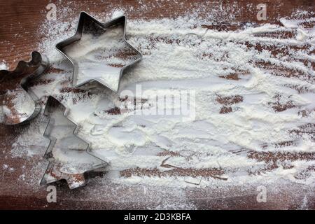 Rentier, weihnachtsbaum und Stern Lebkuchen Ausstechformen und Mehl wie ein Schnee auf Holz Hintergrund. Weihnachten Essen Hintergrund. Draufsicht Stockfoto