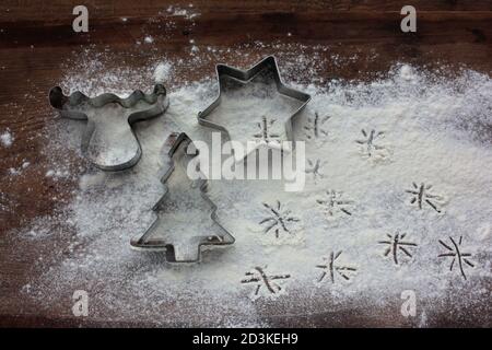 Rentier, weihnachtsbaum und Stern Lebkuchen Ausstechformen und Mehl wie ein Schnee auf Holz Hintergrund. Weihnachten Essen Hintergrund. Draufsicht Stockfoto