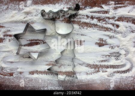 Rentier, weihnachtsbaum und Stern Lebkuchen Ausstechformen und Mehl wie ein Schnee auf Holz Hintergrund. Weihnachten Essen Hintergrund. Draufsicht Stockfoto