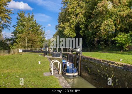 Narrowboat, das durch eine Schleuse am Bruce Branch des Kennet und Avon Canal in Great Bedwyn, einem Dorf im Osten von Wiltshire, Südengland, fährt Stockfoto