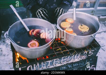 Würziger Glühwein in großen roten Schalen auf dem Weihnachtsmarkt, der Text ist auf russisch und bedeutet genau heißen Wein Stockfoto