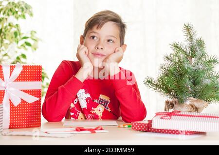 Kleiner Junge schreibt einen Brief an den Weihnachtsmann zu Weihnachten Geschenk und Wünsche Stockfoto