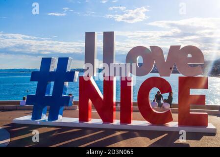 NICE, FRANCE-MAY,29,2019: Tourist poses for a photo near the I love Nice Tourist sign Installation above Promenade des Anglais in City of Nice Stockfoto