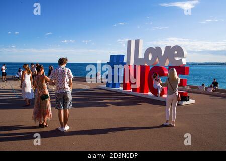NICE, FRANCE-MAY,29,2019: Tourist poses for a photo near the I love Nice Tourist sign Installation above Promenade des Anglais in City of Nice Stockfoto
