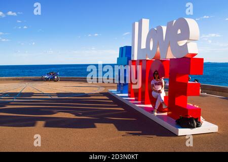 NICE, FRANCE-MAY,29,2019: Tourist poses for a photo near the I love Nice Tourist sign Installation above Promenade des Anglais in City of Nice Stockfoto