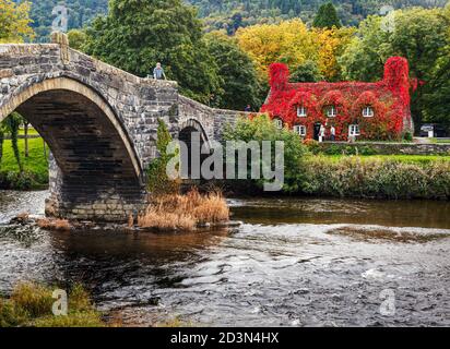 Trefriw, Conwy County, Wales, Vereinigtes Königreich. Die Tu Hwnt i'r Bont Teestube über den Fluss Conwy und Pont Fawr, oder Große Brücke gesehen. Die Teestube i Stockfoto