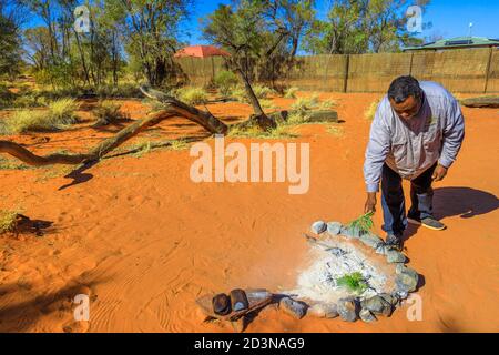 Kings Creek, Australien - 21. Aug 2019: aborigines verbrennt Pflanzen auf Feuer, umgeben von Steinen. Pflanzen haben spezielle reinigende Eigenschaften beim Rauchen Stockfoto