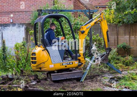 Gartenarbeit und Renovierung Teilnahme an Garten in Bournemouth, Dorset UK im Oktober - Arbeiter Betrieb jcb Mini Bagger Stockfoto