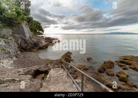 Morgendämmerung an einem Betonstrand mit einer Leiter aus Edelstahl Stockfoto