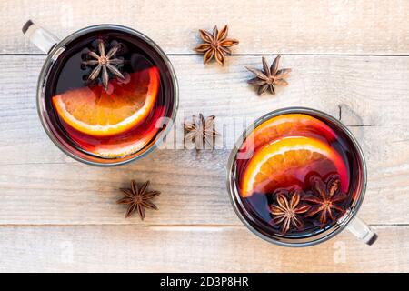 Draufsicht zwei Gläser Glühwein mit Gewürzen und Orangenscheiben auf Holzhintergrund. Stockfoto