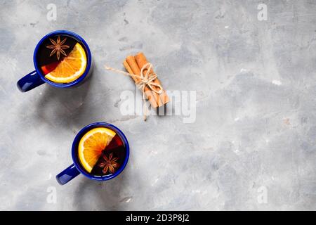Draufsicht zwei Tassen Glühwein mit Gewürzen und Orangenscheiben auf grauem Hintergrund mit Kopierraum. Stockfoto