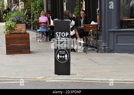 Menschen, die an einem Stop vorbeigehen das Coronavirus Straßenschild in Covent Garden, London, 2020. Um die Straßen und den Markt von Covent Garden herum wurden Schilder angebracht, um die soziale Distanzierung zu fördern. Stockfoto