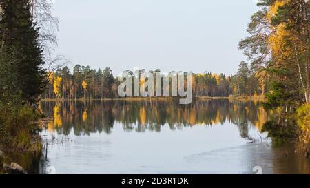 Toller Blick auf den See, Pinienwald am Ufer und mit Kiefern bedeckte Inseln. Stille des guten Herbsttages. Wunderbare Reflexionen der Herbstbäume im Wasser. Stockfoto