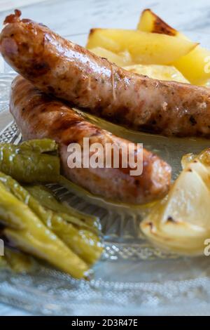 Nahaufnahme der spanischen Schweinswürste (butifarras) mit Kartoffeln, Zwiebeln und gerösteten Tomaten Stockfoto