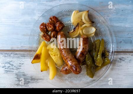 Nahaufnahme der spanischen Schweinswürste (butifarras) mit Kartoffeln, Zwiebeln und gerösteten Tomaten Stockfoto