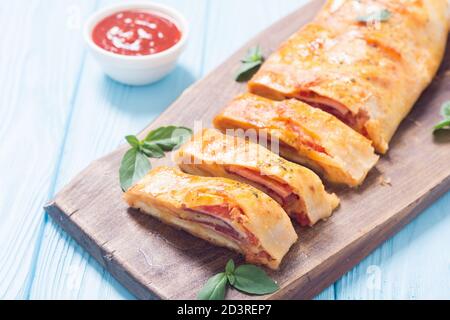 Italienische Küche Pizzarolle stromboli mit Käse, Salami, Oliven und Tomaten Stockfoto