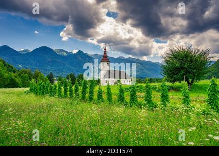 Kirche mit landwirtschaftlicher Umgebung im slowenischen Alpenraum. Stockfoto