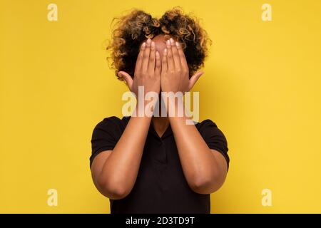 Junge afrikanische Frau bedeckt Gesicht mit Händen versteckt ihre Emotionen vor allen. Stockfoto