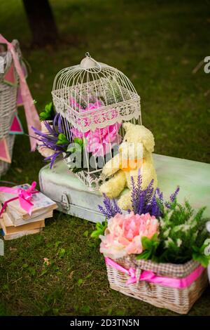 Straßendekorationen für eine Kinderparty. Retro Koffer mit Blumen mit einem Teddybären in einem grünen Park. Party auf der Straße. Stockfoto