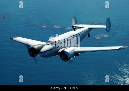 Ein Luft-zu-Luft-Porträt eines zweimotorigen Transportflugzeugs der 1930er Jahre, das über den Ozean fliegt. Beech 18 Stockfoto