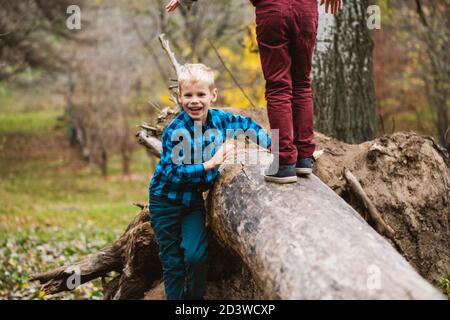 Zwei präteen männlich neugierige Kinder klettern und spielen mit riesigen gefallenen Baumstamm im Herbst Park, aktiv glückliche Kindheit Stockfoto