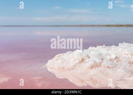 Salz rosa Kristalle Haufen Nahaufnahme leuchtet an der Seeufer mit rosa Wasseroberfläche Reflexion. Spa-Erholung Stockfoto