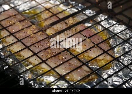 Fischfilets in Folie, die mit einem Braai-Gitter und heißen Kohlen gekocht werden. Südafrikanische Lebensmittel Konzept Foto Stockfoto